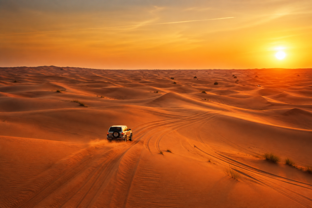 4x4 driving across Lahbab-style red sand dunes at sunset